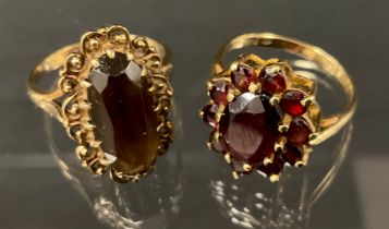 A deep red garnet oval panel ring, 9ct gold shank, size L/M,3.8g gross, another oval cluster ring,