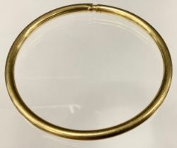 A yellow metal hollow tubular compression bangle, stamped 585, 10g