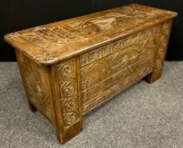 A carved oak blanket chest/coffer, the lift-up lid caved with faux hinge straps, and portrait bust