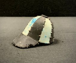 An early 20th century novelty Jockeys cap pin cushion, in blue and black panels, black peak, 5cm x