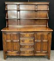 An Ercol elm dresser, with two-tier plate rack top, above a rounded rectangular top, and central row