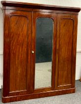 A Victorian mahogany compactum triple wardrobe, serpentine-shaped cornice, above two arch-panelled