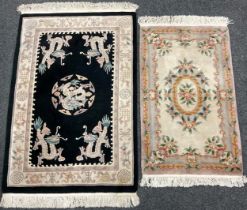 A Chinese wool pile carpet, knotted with dragons and stylised flowers in cream and pink on a black