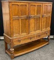 A mid 20th century oak three-door bow-front buffet side cabinet, carved panelled doors, above a pair