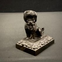 A Bronze cast iron weighted desk weight, as a seated Spaniel, floral plinth, 7.6cm high, c.1920