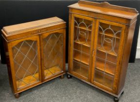 An early 20th century oak bookcase cabinet, quarter galleried top, carved decoration to frieze,