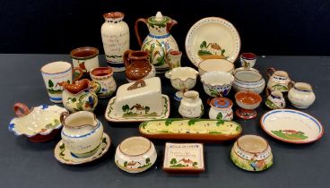 A collection of Torquay motto ware including; butter dish, cups and vases; etc