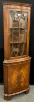 A reproduction Georgian style corner cabinet, dentil cornice, astral-glazed top door enclosing two