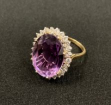 A diamond and amethyst cluster ring, large oval mixed cut amethyst approx 10.00ct, surrounded by a