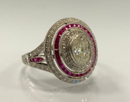 A diamond and ruby ring, stepped oval platform with raised central oval diamond approx 0.70ct,