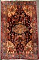 A Persian Navahand rug / carpet, hand-knotted with oval-shaped medallion, within a field of stylised