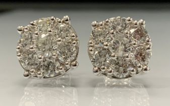 A pair of impressive diamond cluster earrings, each set with seven round brilliant cut diamonds,