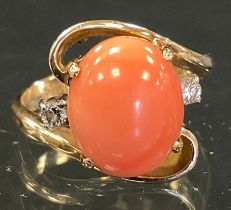 A coral and diamond ring, central pink coral cabochon, flanked by round brilliant cut diamond