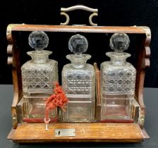 A late Victorian oak three-bottle tantalus, c.1890