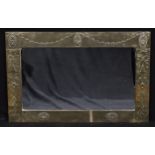 An Arts & Crafts brass mounted chimney glass, rectangular mirror plate, the frame repoussé decorated