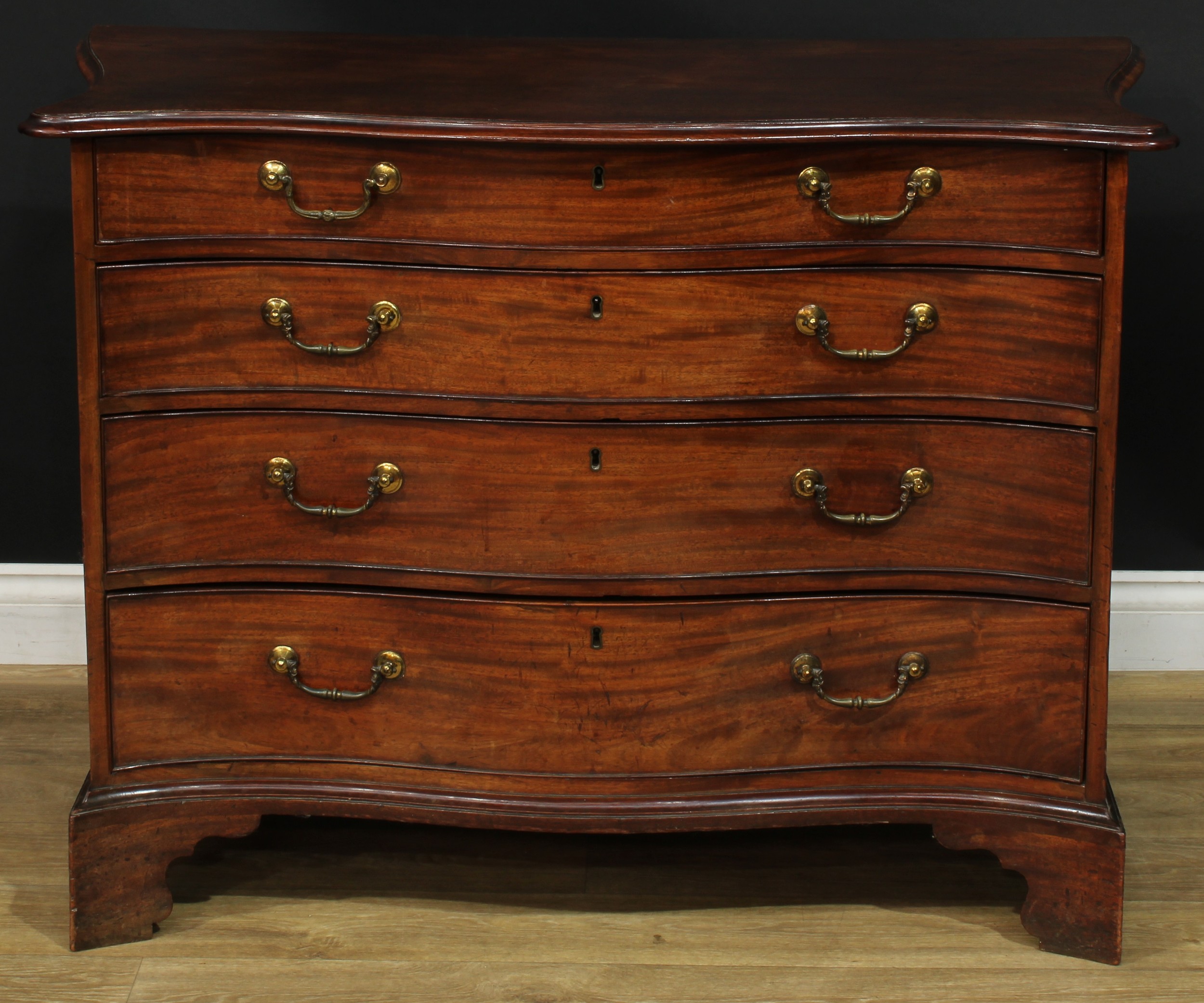 A George III mahogany serpentine chest, slightly oversailing top with moulded edge above four long