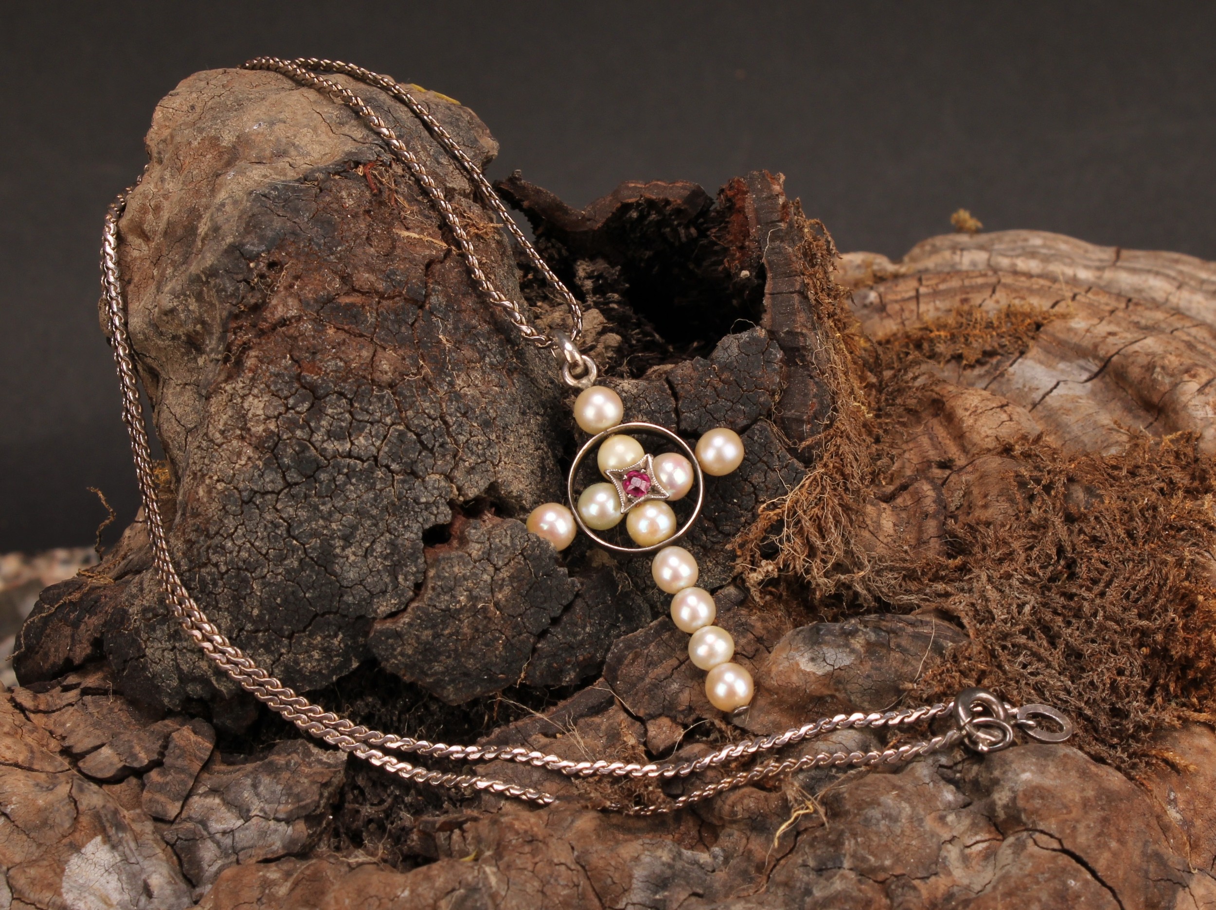 A natural pearl and spinel crucifix pendant, centred by a round cut pink stone, silver chain