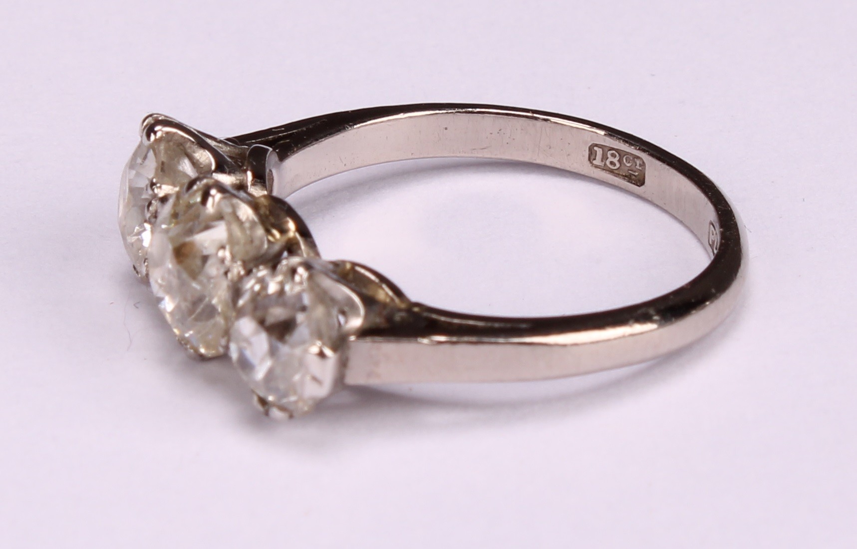 A diamond three stone ring, the central round brilliant cut stone flanked by two smaller stones, - Image 3 of 4