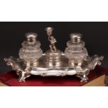 A Victorian silver fluted cartouche shaped inkstand, central amorini figural taperstick flanked by a