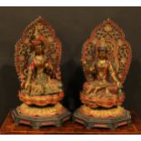 A pair of polychrome and gilt painted hardwood shrine figures, as bodhisattva, each seated upon a