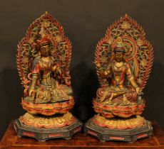 A pair of polychrome and gilt painted hardwood shrine figures, as bodhisattva, each seated upon a