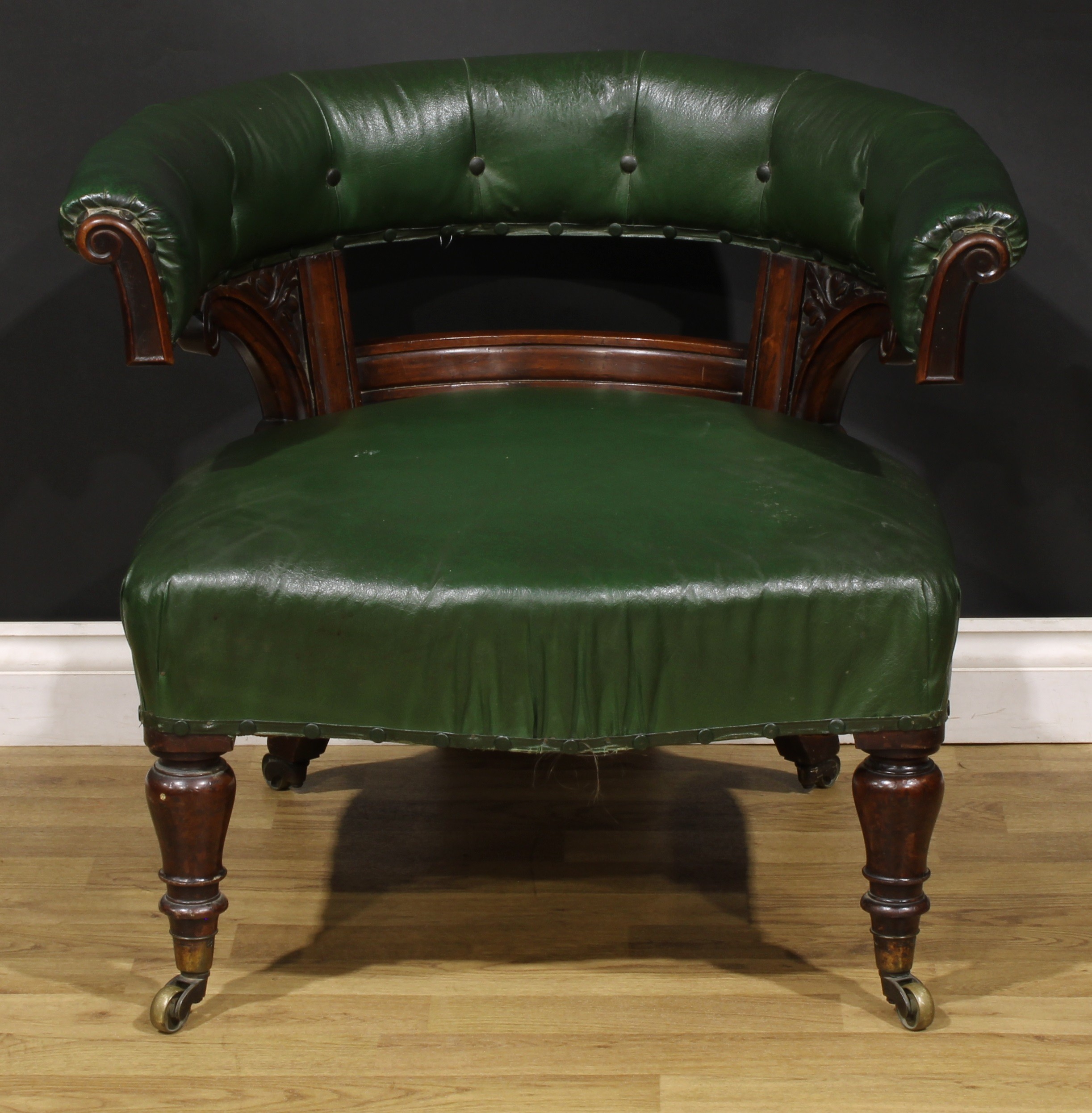 A Victorian rosewood and mahogany club library chair, stuffed-over upholstery, turned forelegs,