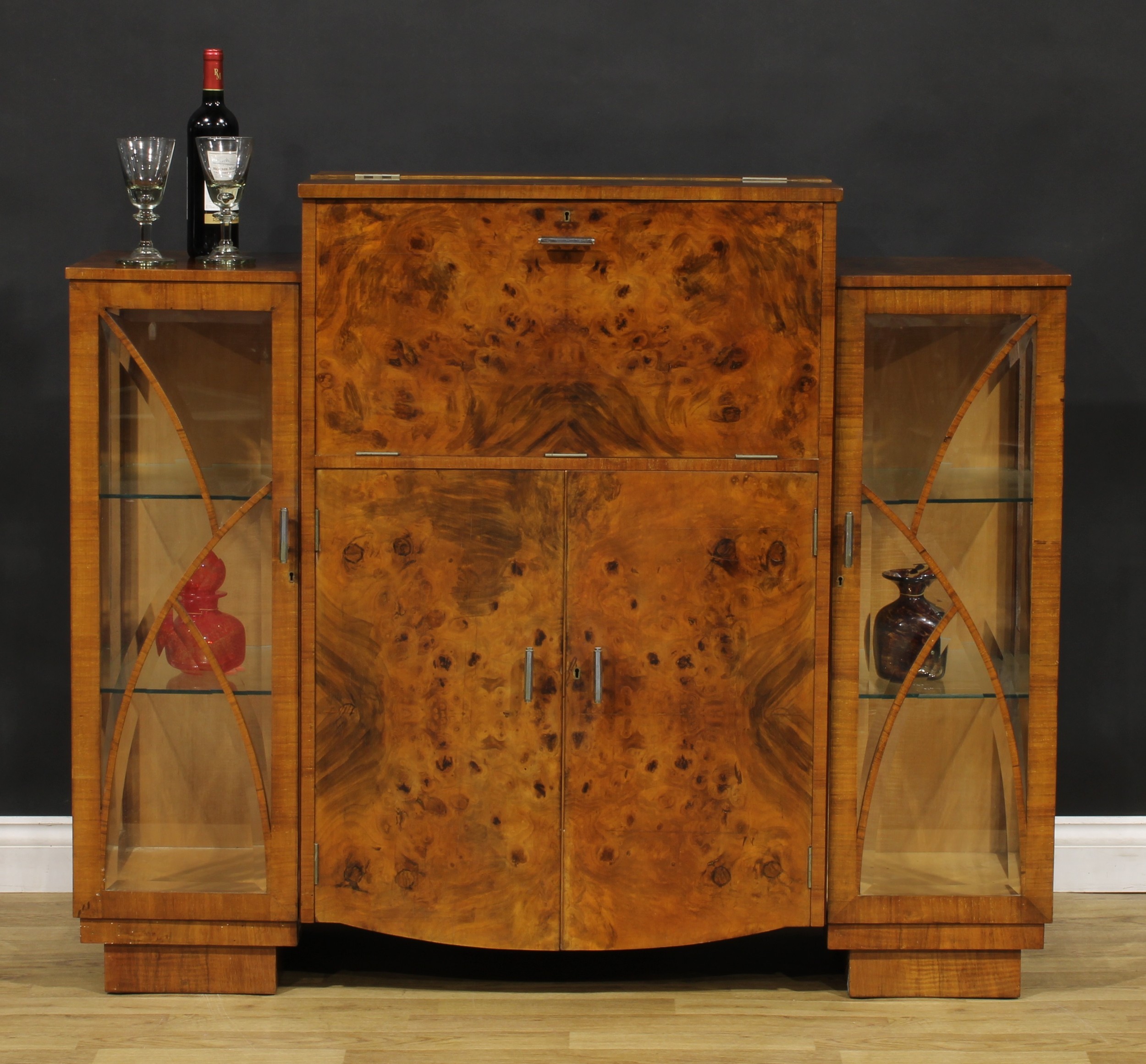 An Art Deco burr walnut cocktail cabinet, hinged top and fall front enclosing a fitted interior,