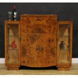 An Art Deco burr walnut cocktail cabinet, hinged top and fall front enclosing a fitted interior,