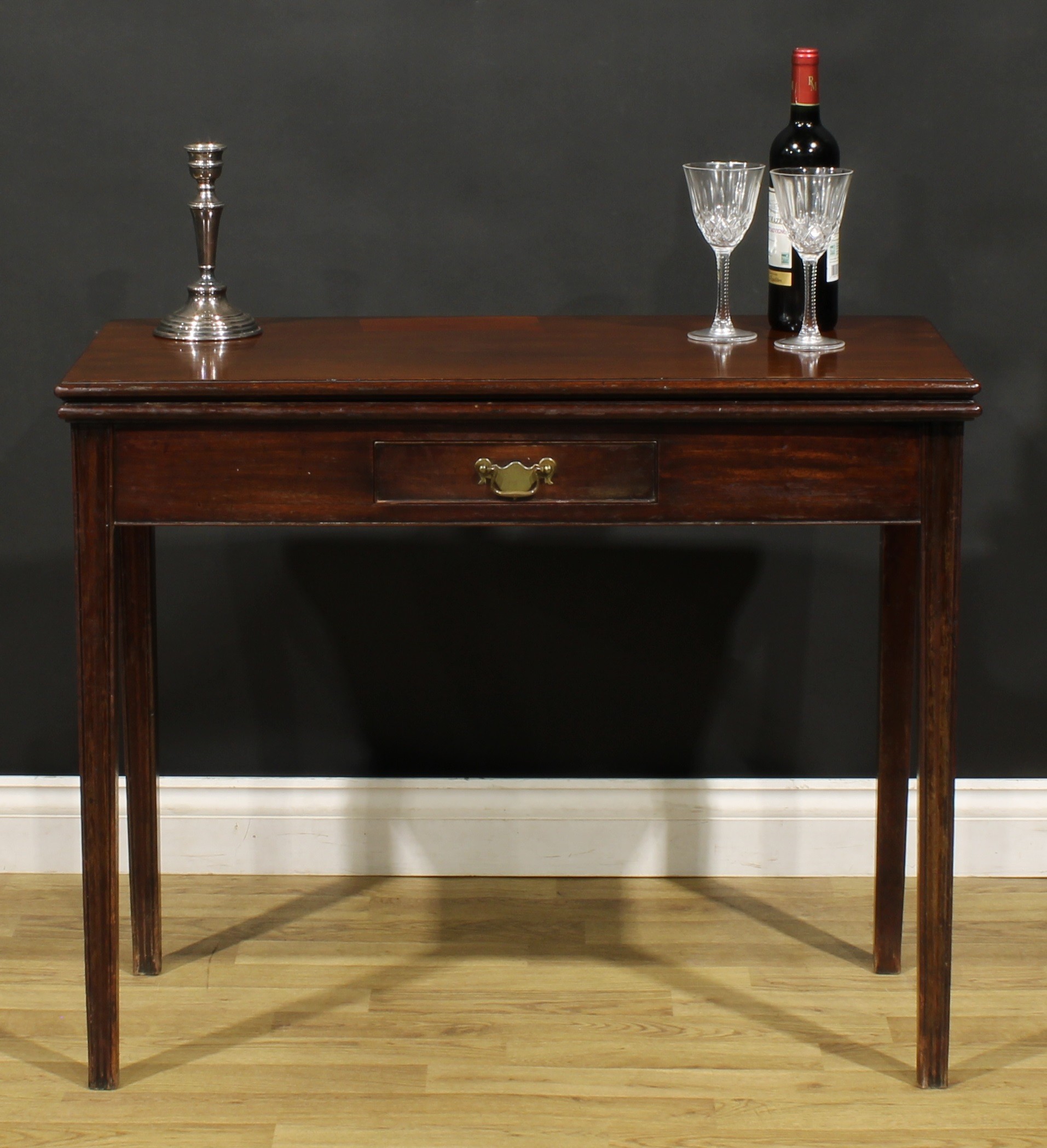 A George III mahogany card table, hinged top with moulded edge enclosing a baize lined playing