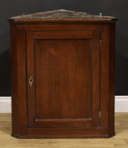 A George III mahogany wall hanging splay front corner cabinet, moulded cornice above a panel door