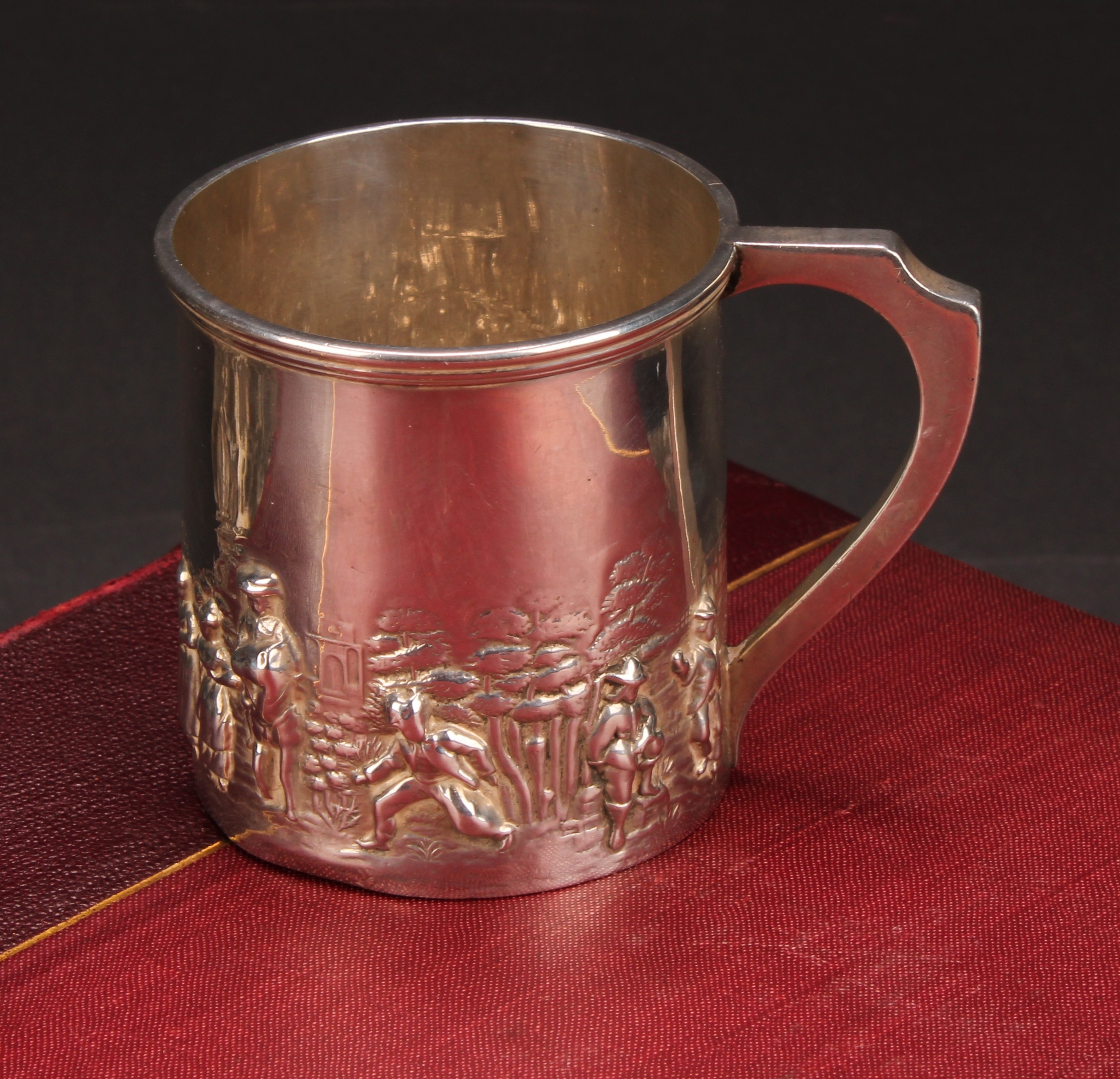 An Edwardian silver Christening mug, chased with a band of figures in the manner of Teniers, 6.5cm