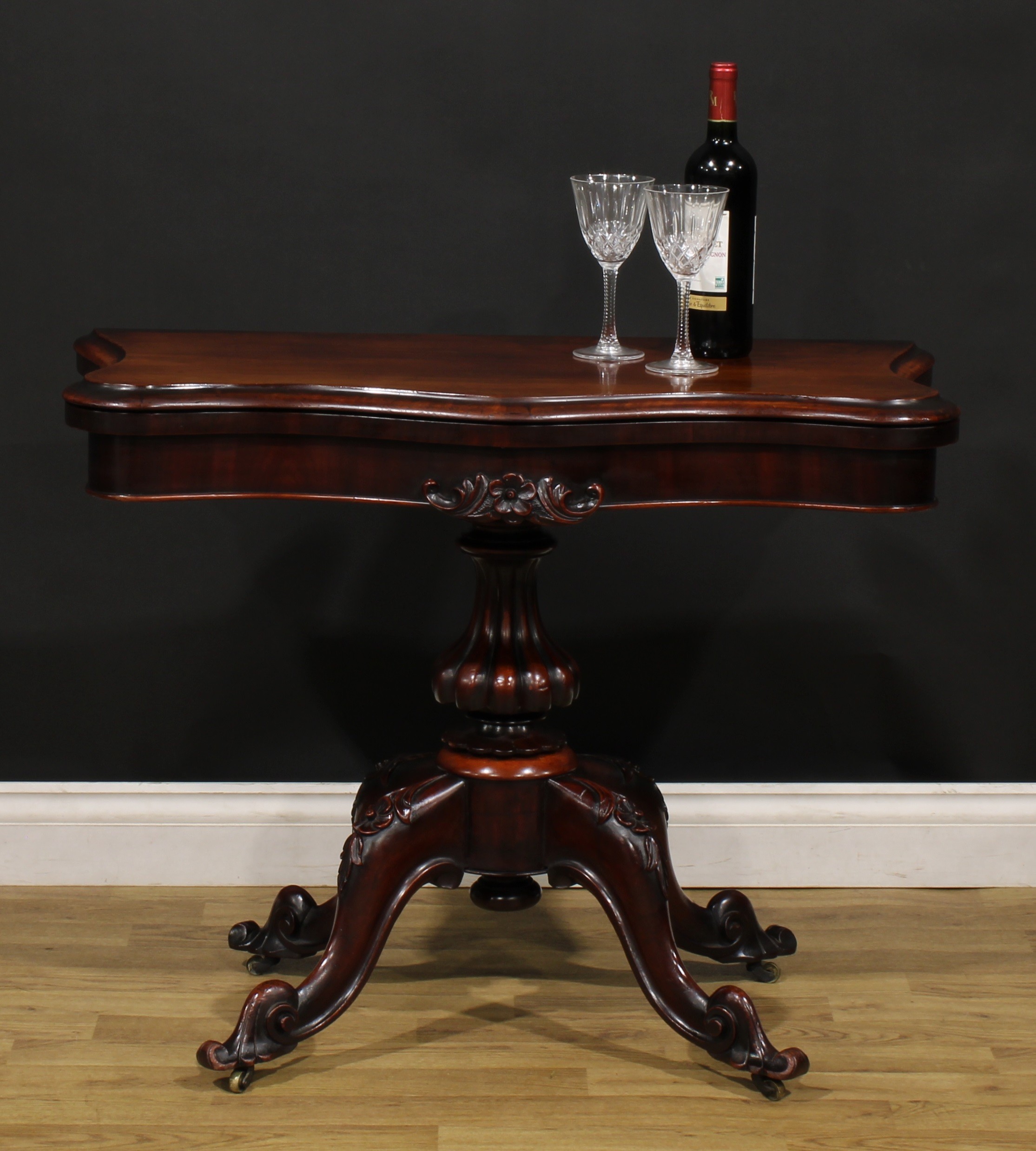 A Victorian mahogany serpentine card table, hinged top with moulded edge enclosing a baize lined
