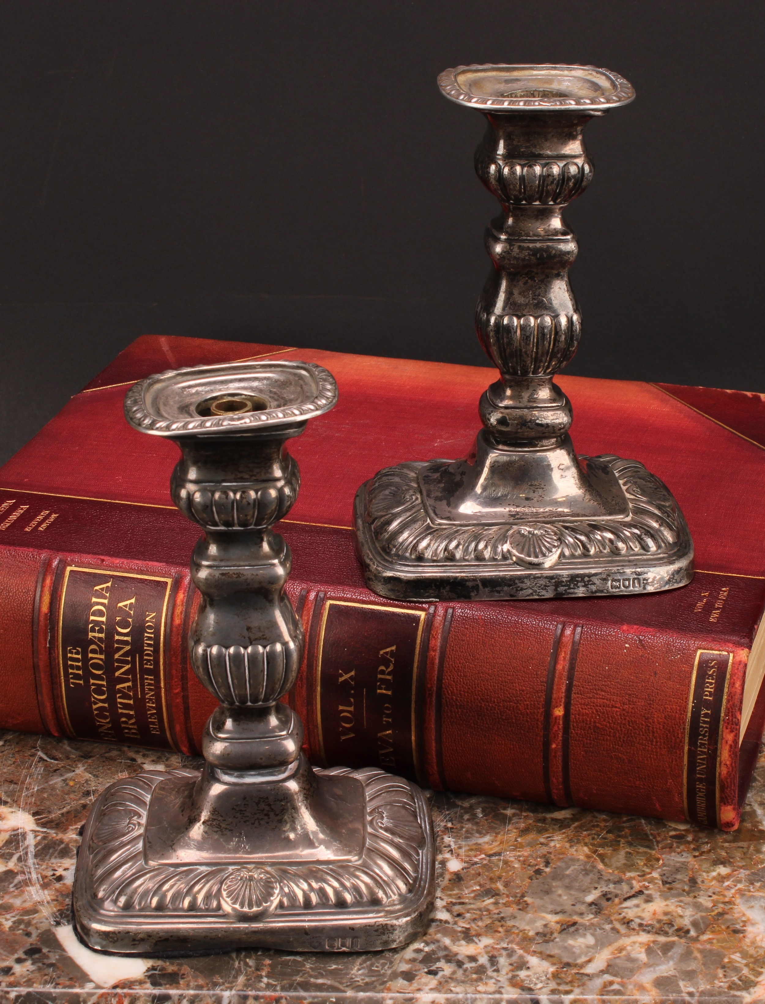 A pair of Edwardian silver rounded rectangular candlesticks, fluted borders, shells to bases, 18cm