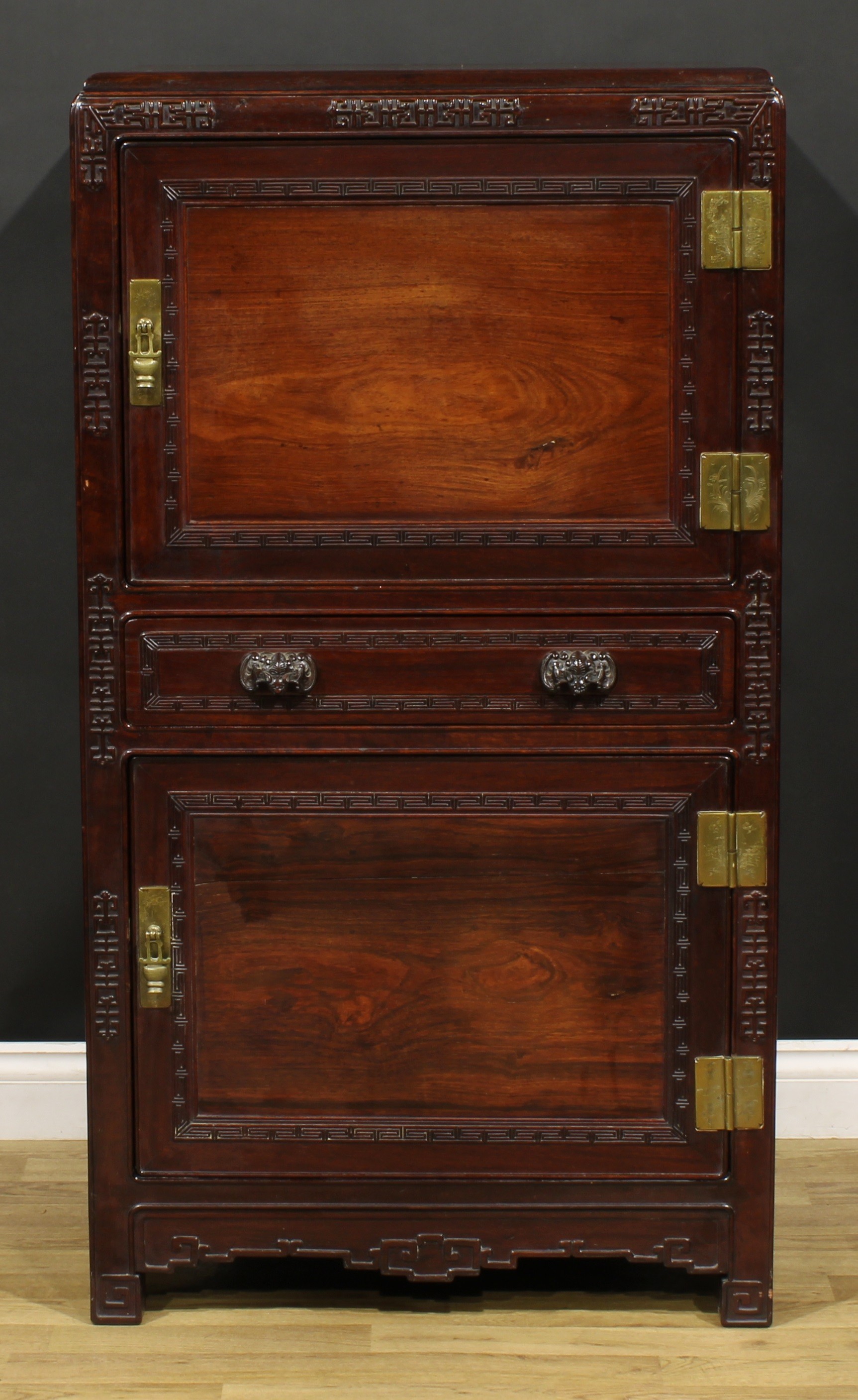 A Chinese hardwood side cabinet, moulded rectangular top above two panel doors centred by a long