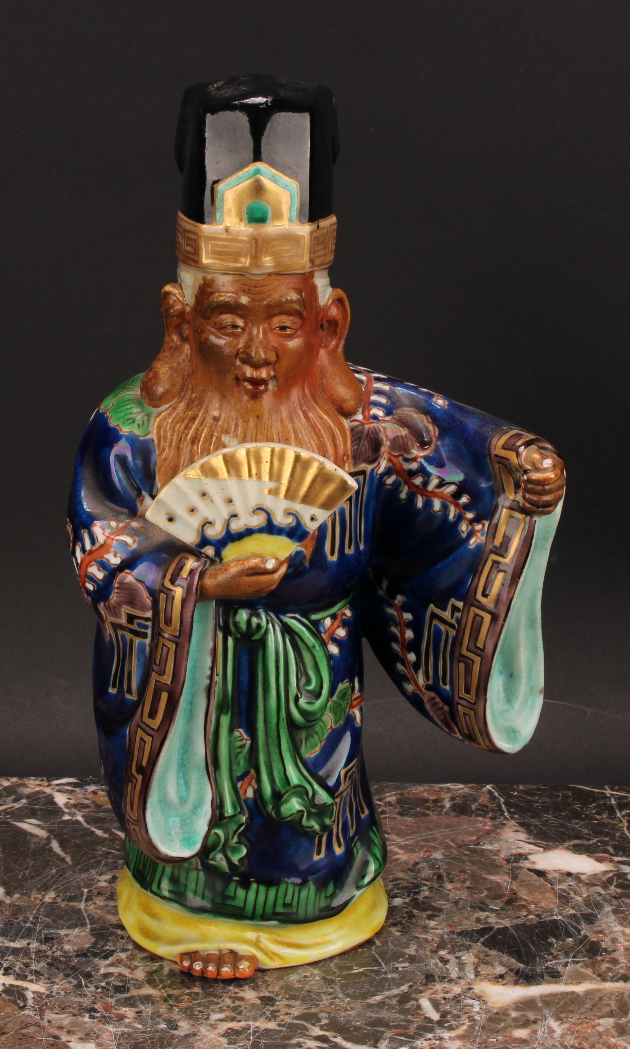 A Japanese porcelain figure, of an elder holding a fan, painted in polychrome and picked out in - Image 2 of 6