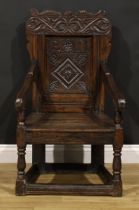 A 17th century oak wainscot armchair, shaped cresting carved with scrolling leafy branches, the