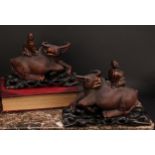A pair of Chinese hardwood carvings, of boys riding buffalo, pierced hardwood stands, 32cm wide, c.
