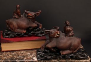 A pair of Chinese hardwood carvings, of boys riding buffalo, pierced hardwood stands, 32cm wide, c.