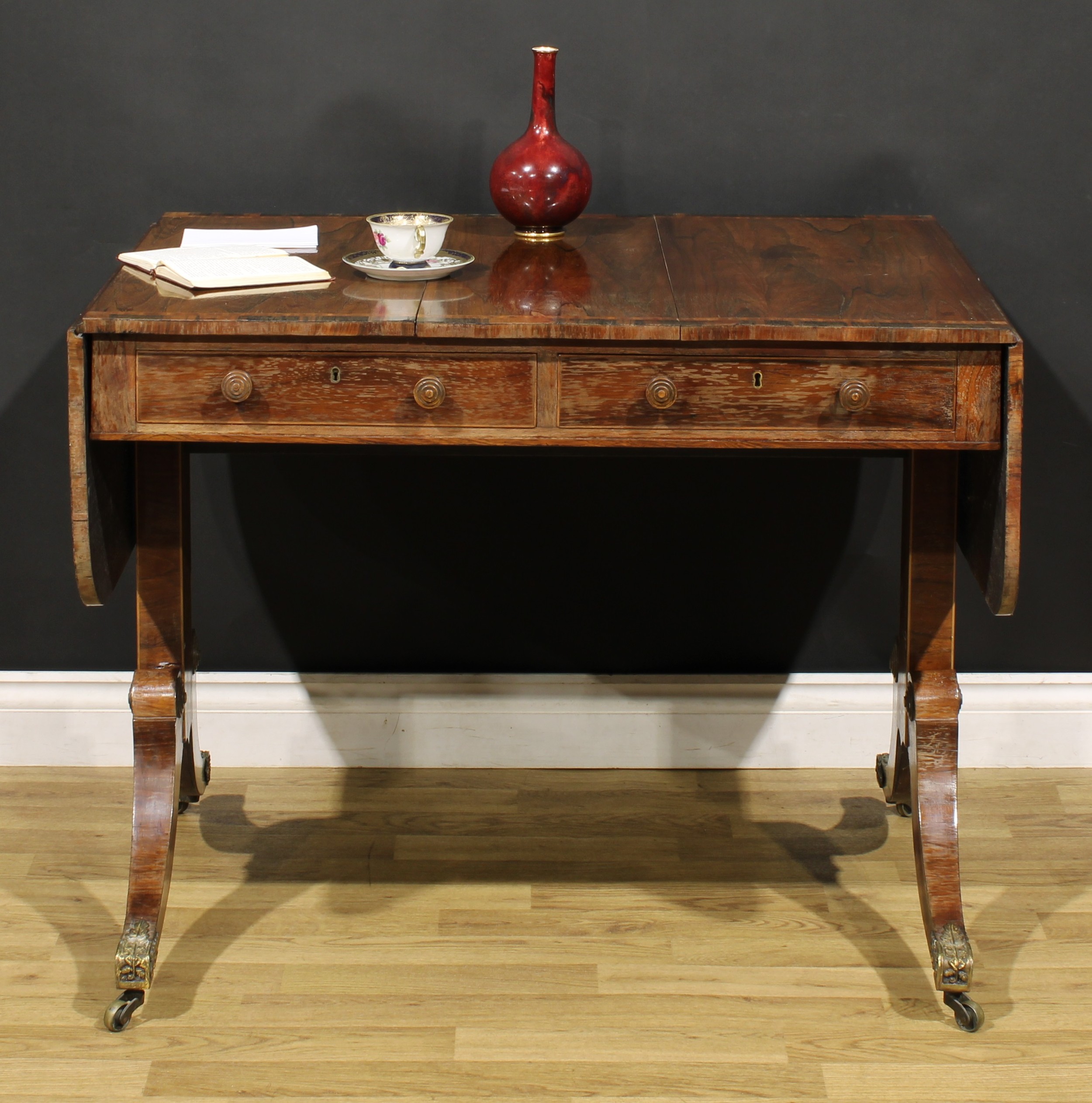 A Regency rosewood sofa table, crossbanded rounded rectangular top with fall leaves, above a pair of