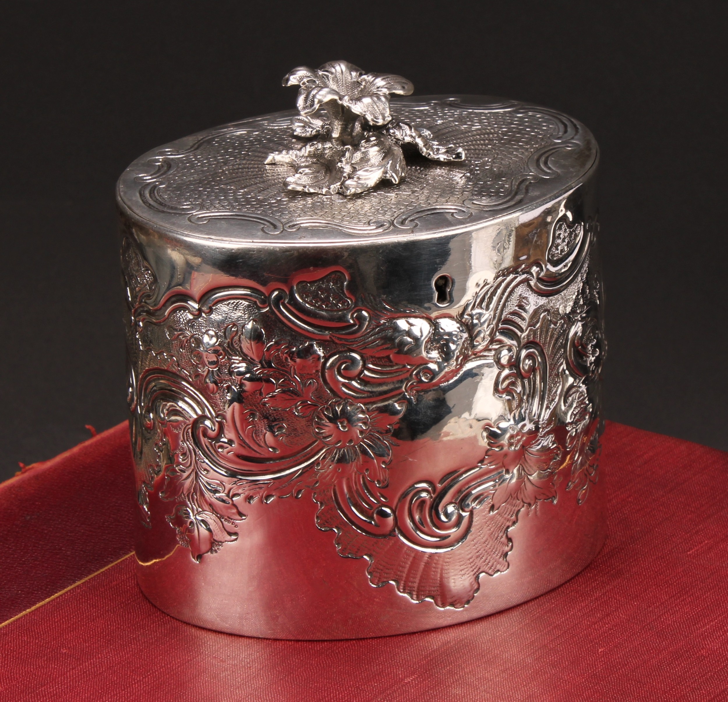 A George III oval tea caddy, chased with birds, flowers and scrolling leaves, flush-hinged cover