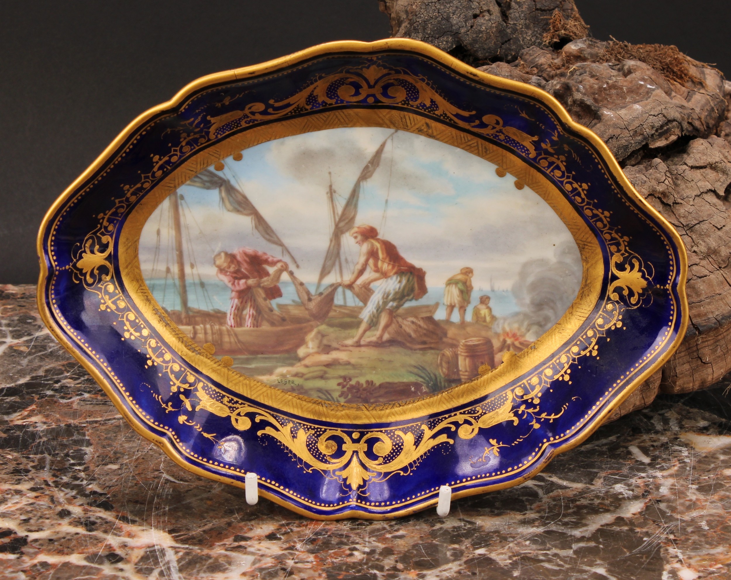 A Sevres shaped oval dish, painted by Leber, signed, with fishermen unloading their catch, the