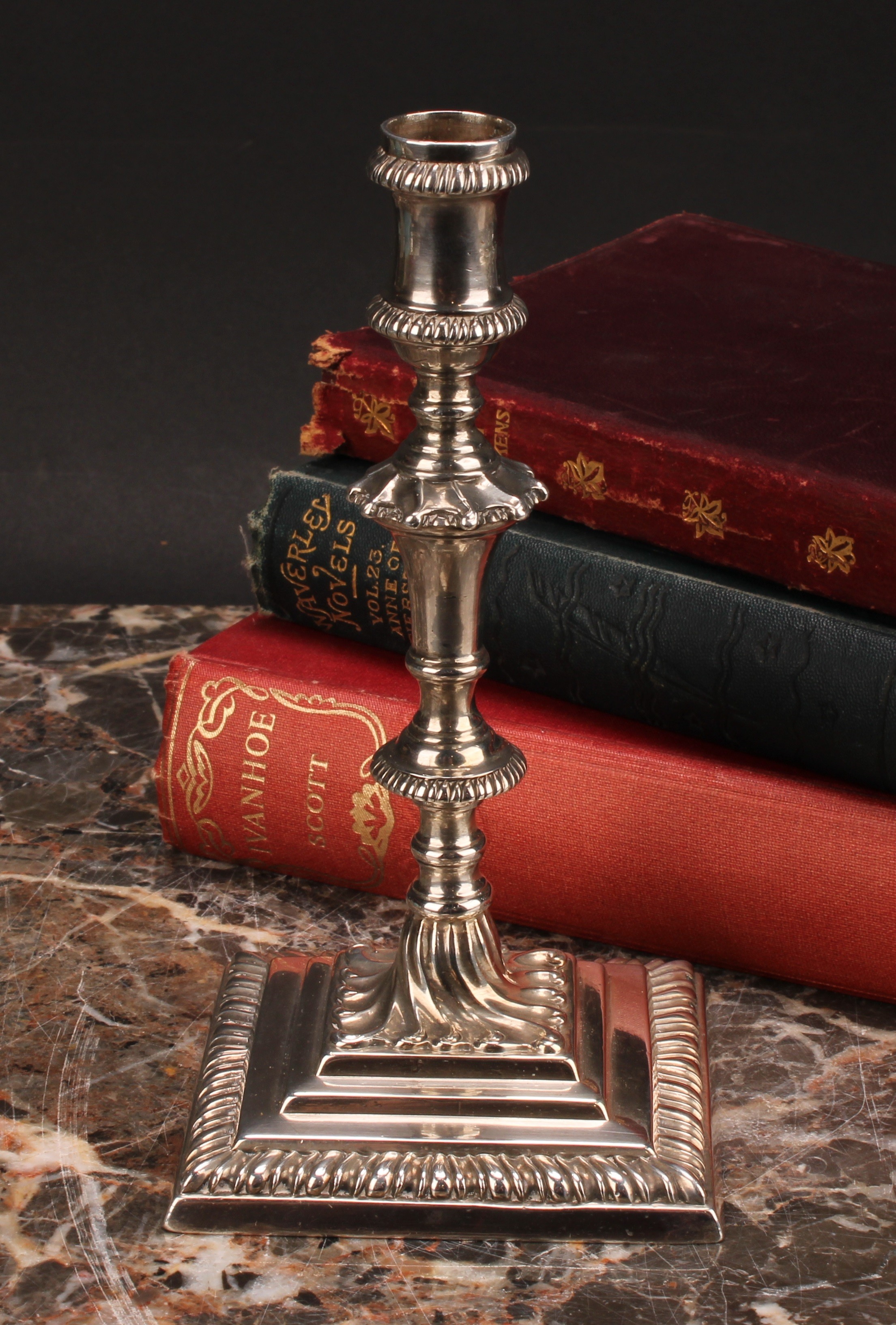 An early George III cast silver taperstick, knopped pillar, stepped square base with gadrooned