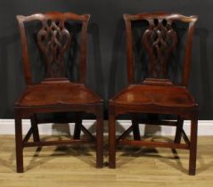 A pair of George III red walnut/mahogany hall chairs, each with Cupid’s bow cresting rail above a