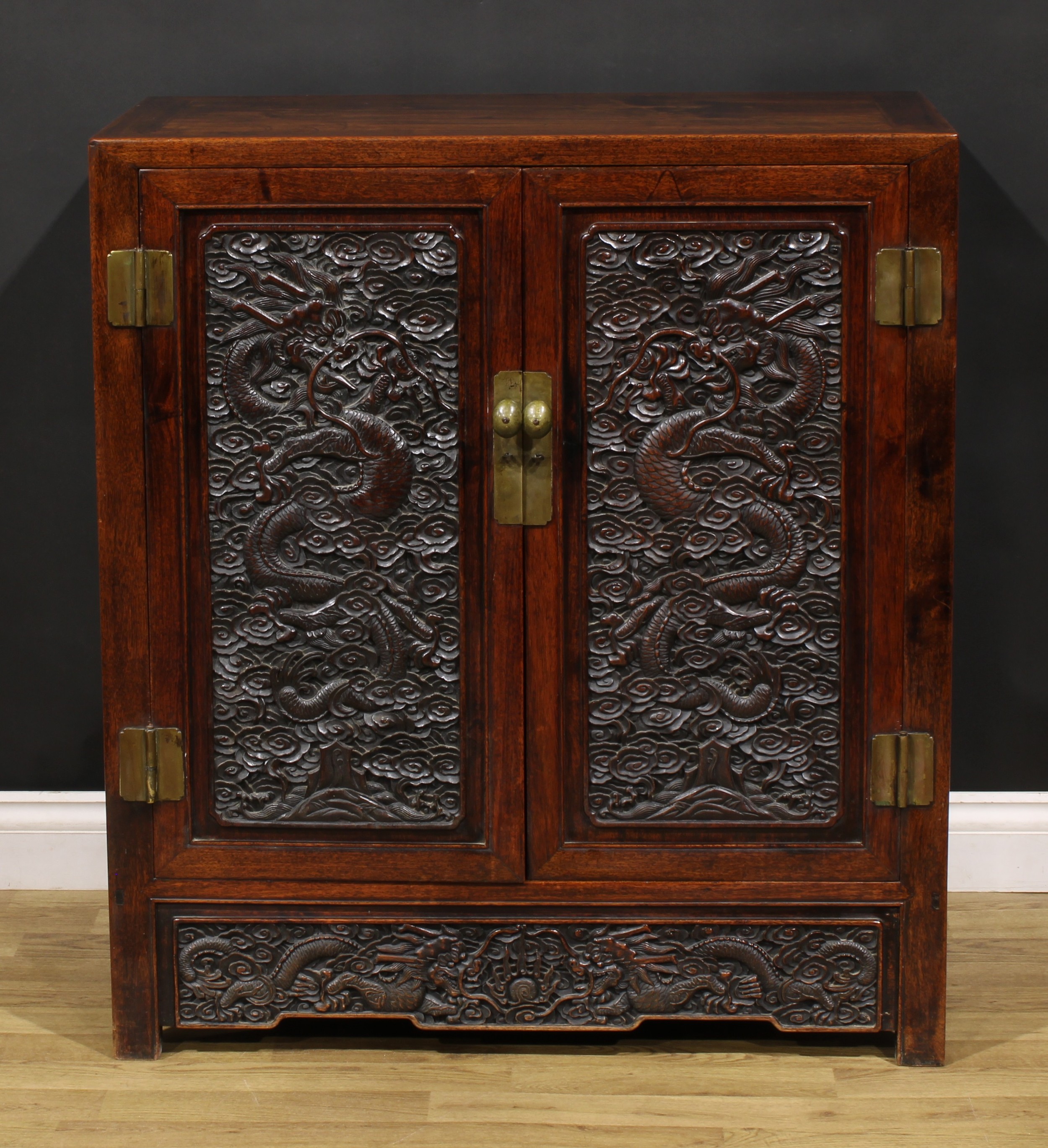 A Chinese hardwood side cabinet, flush rectangular top above a pair of panel doors, each carved with