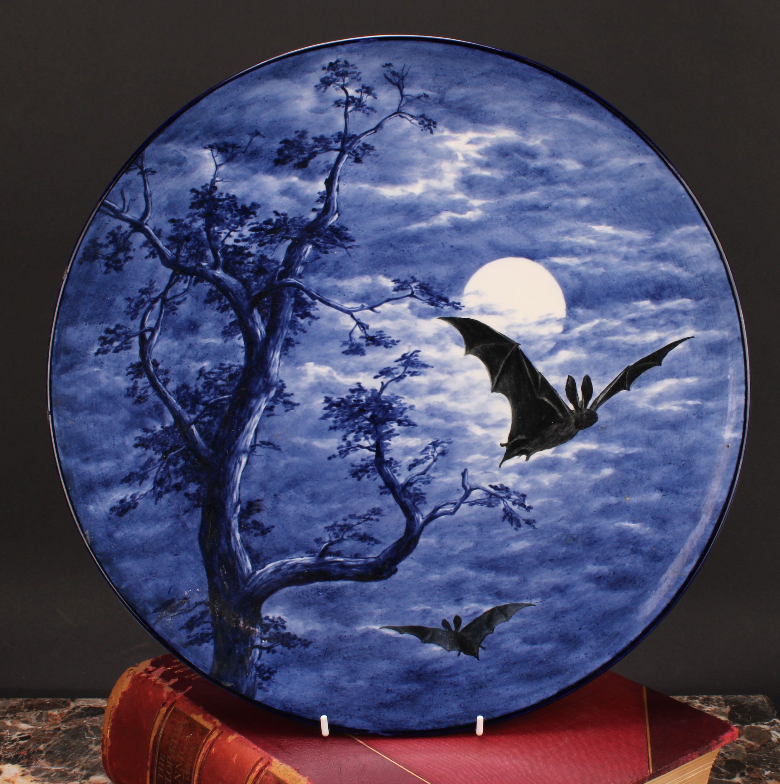 A Royal Worcester Aesthetic Movement circular charger, painted with bats against a moonlit sky, in
