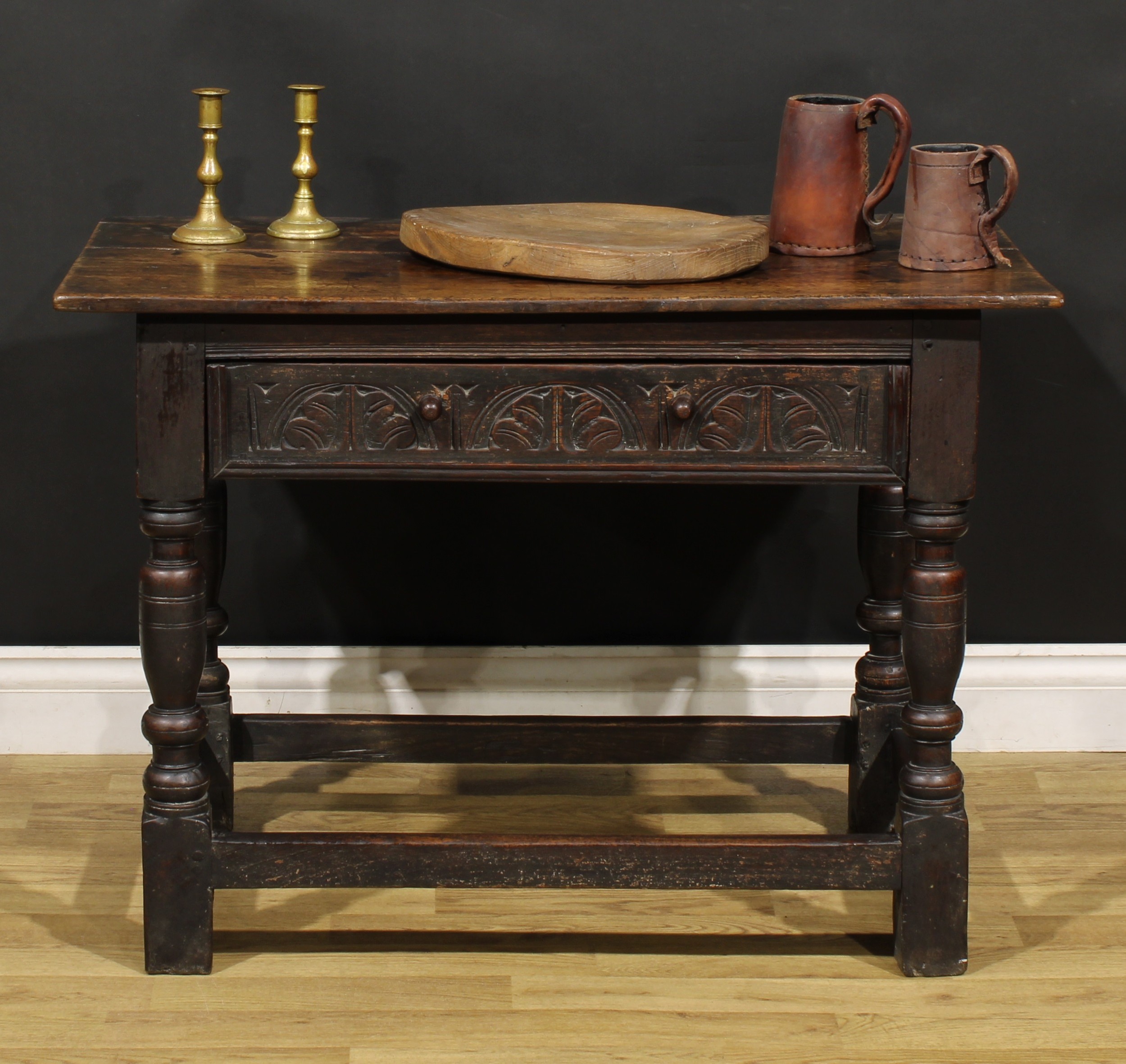 A 17th century oak side table, oversailing top above a long frieze drawer carved with leafy