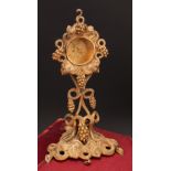 An early 20th century gilt metal pocket watch stand, cast throughout with fruiting vine, triform