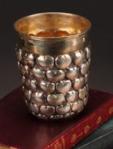 A German silver snakeskin type beaker, chased with rows of hearts, gilt interior, 9.5cm high, 13