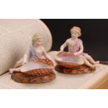 A pair of 19th century Sitzendorf figural table salts, of children holding seashells, decorated in