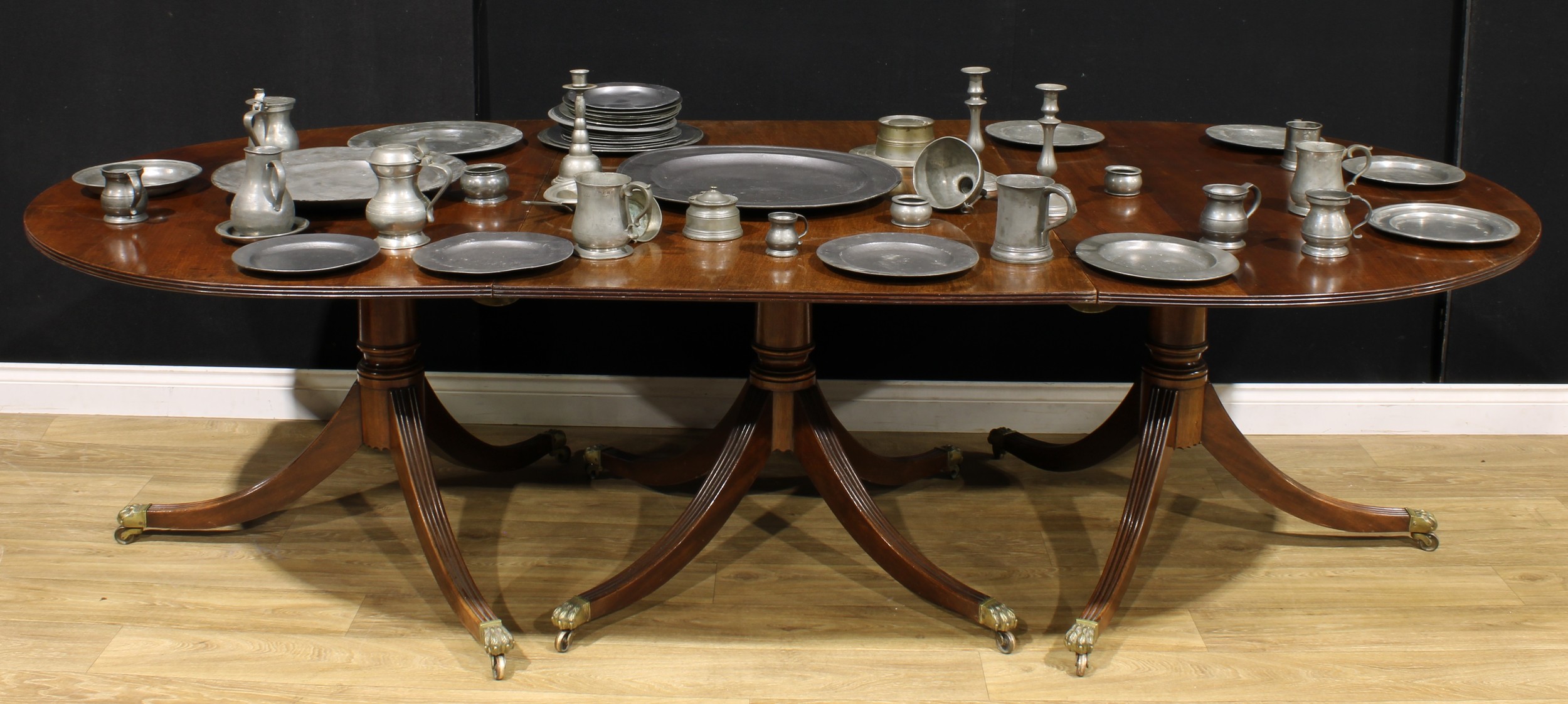 A large Regency Revival mahogany triple-pillar dining table, discorectangular top with reeded edge,